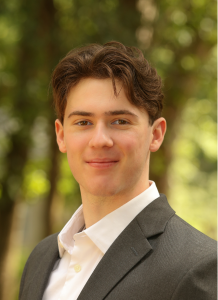 Picture of young man outside wearing a suit jacket and open collar